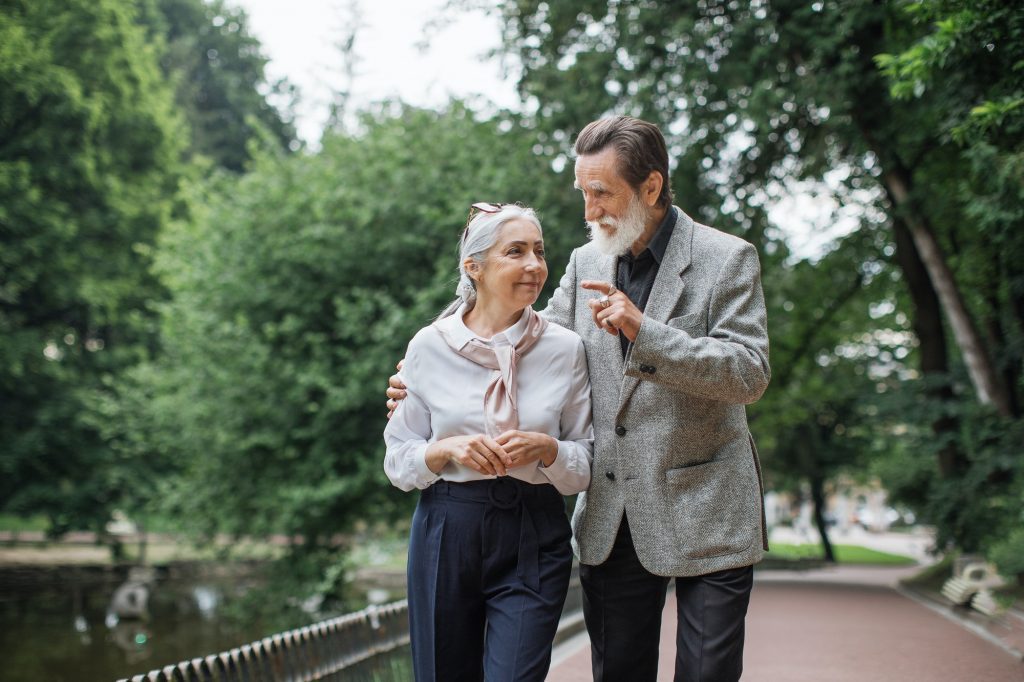 Happy senior couple walking in the park in Vancouver while they discuss Medicare in the state.